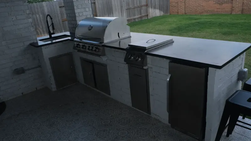 Built-in gas grill and stainless access doors in the white brick island