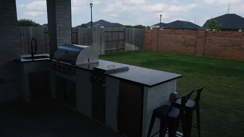Outdoor kitchen with built-in grill, side burner and bar seating in Cypress