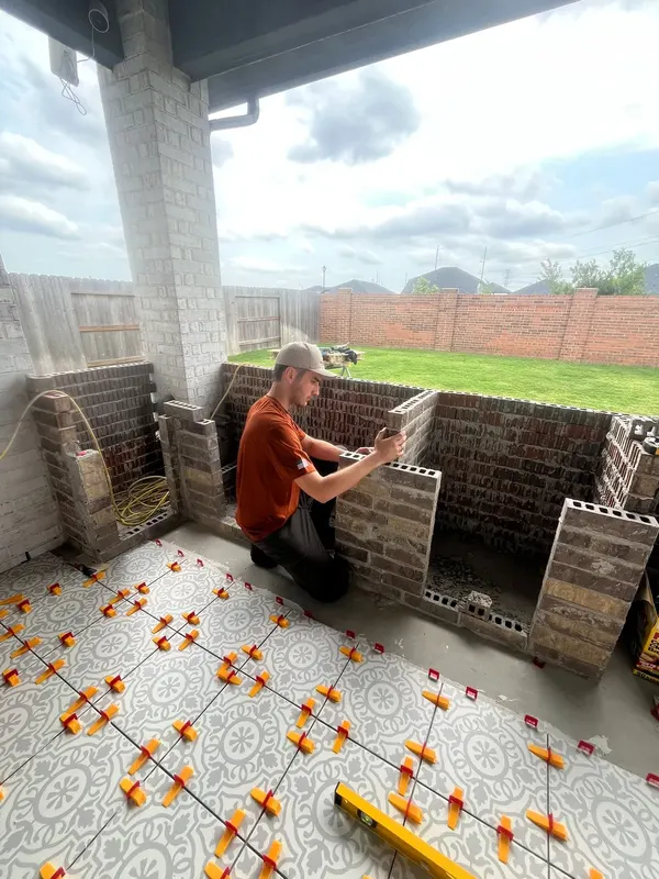 KRM mason building the brick island on the tiled patio