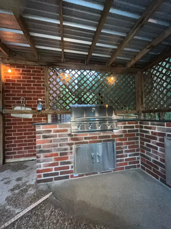 Built-in stainless gas grill and access doors in the red brick island