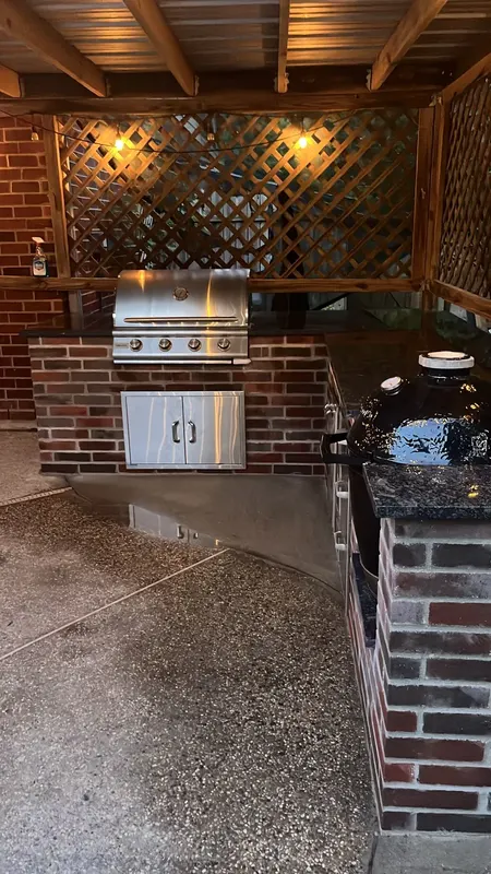 Grill, stainless doors and kamado cooker on the black granite counter