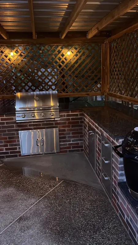 L-shaped brick outdoor kitchen with grill and stainless doors