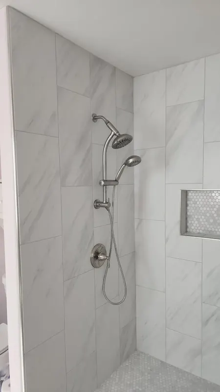 Rain shower head and handheld on the marble-look tile wall