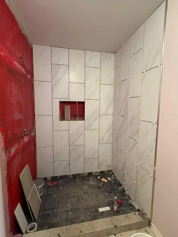 Large-format tile going up over the waterproofed walls
